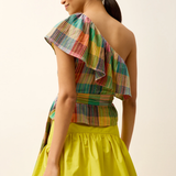 Woman wearing a colorful one-shoulder top and yellow skirt against a plain background