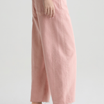 Person wearing pink pants and brown shoes on a white background