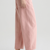 Person wearing pink pants and brown shoes on a white background