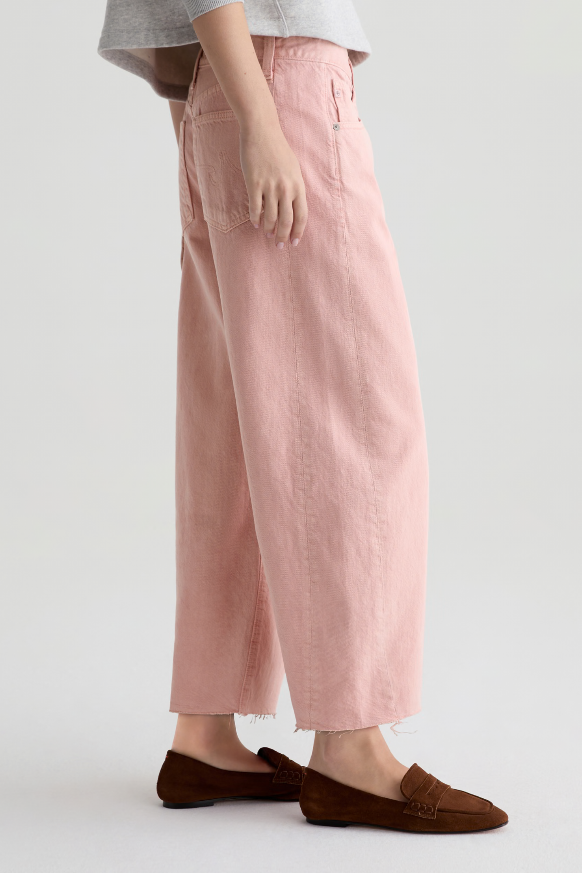 Person wearing pink pants and brown shoes on a white background