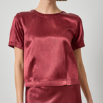 Woman wearing a red satin top and skirt on a plain background