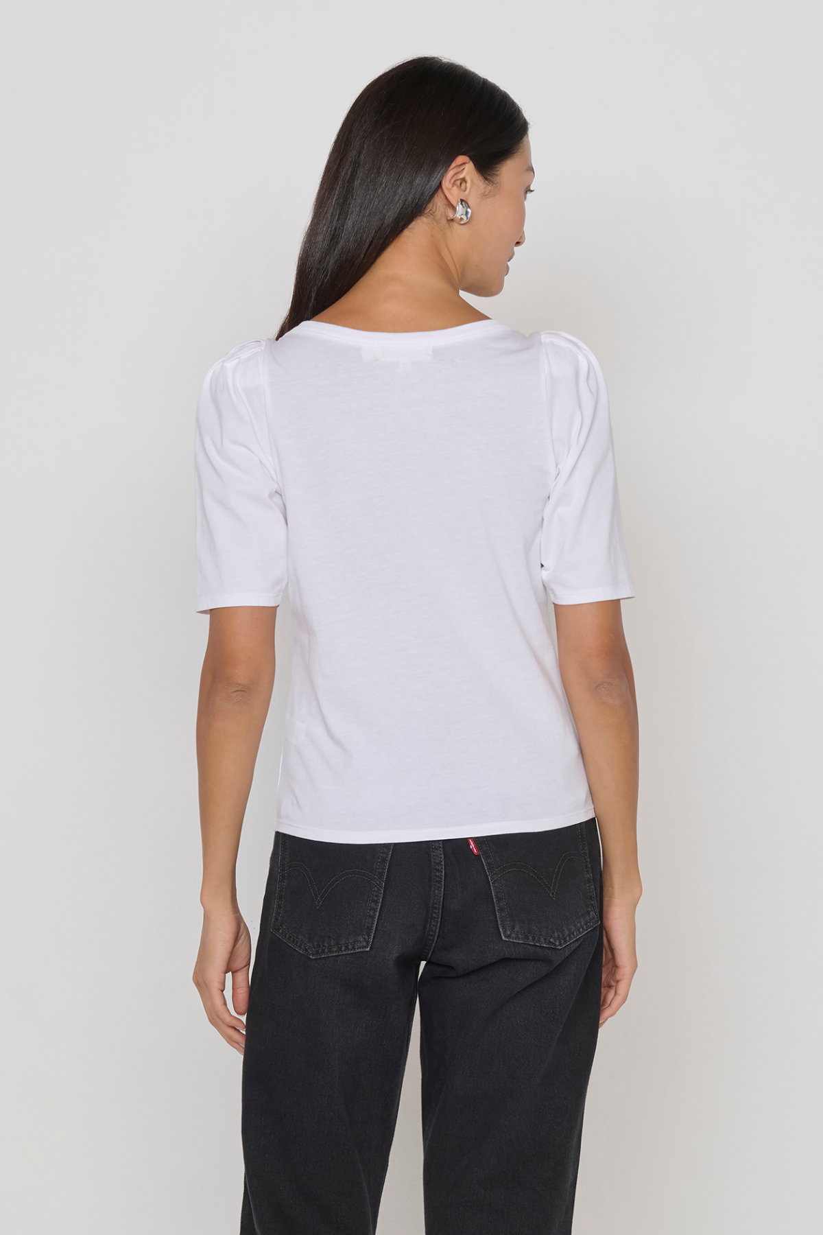 Person wearing a white t-shirt and black pants on a plain background