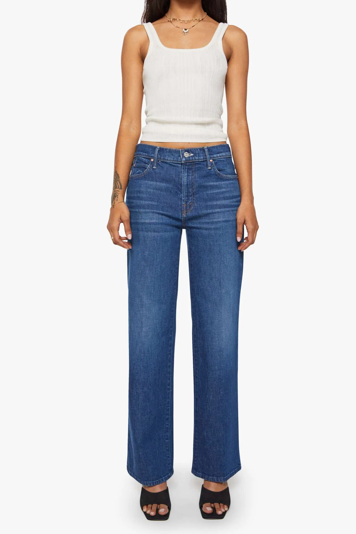 Person wearing blue jeans and a white crop top on a white background