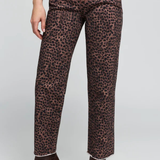 A model wearing leopard print cropped jeans with a brown and black animal pattern, paired with dark brown pointed-toe ankle boots, shown against a light gray studio background.