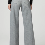 A person shown from the back wearing light gray wide-leg jeans, a black long-sleeve top, and black heels against a plain light gray studio background.