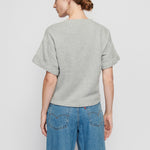 Person wearing a gray sweater and blue jeans on a plain background