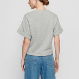 Person wearing a gray sweater and blue jeans on a plain background