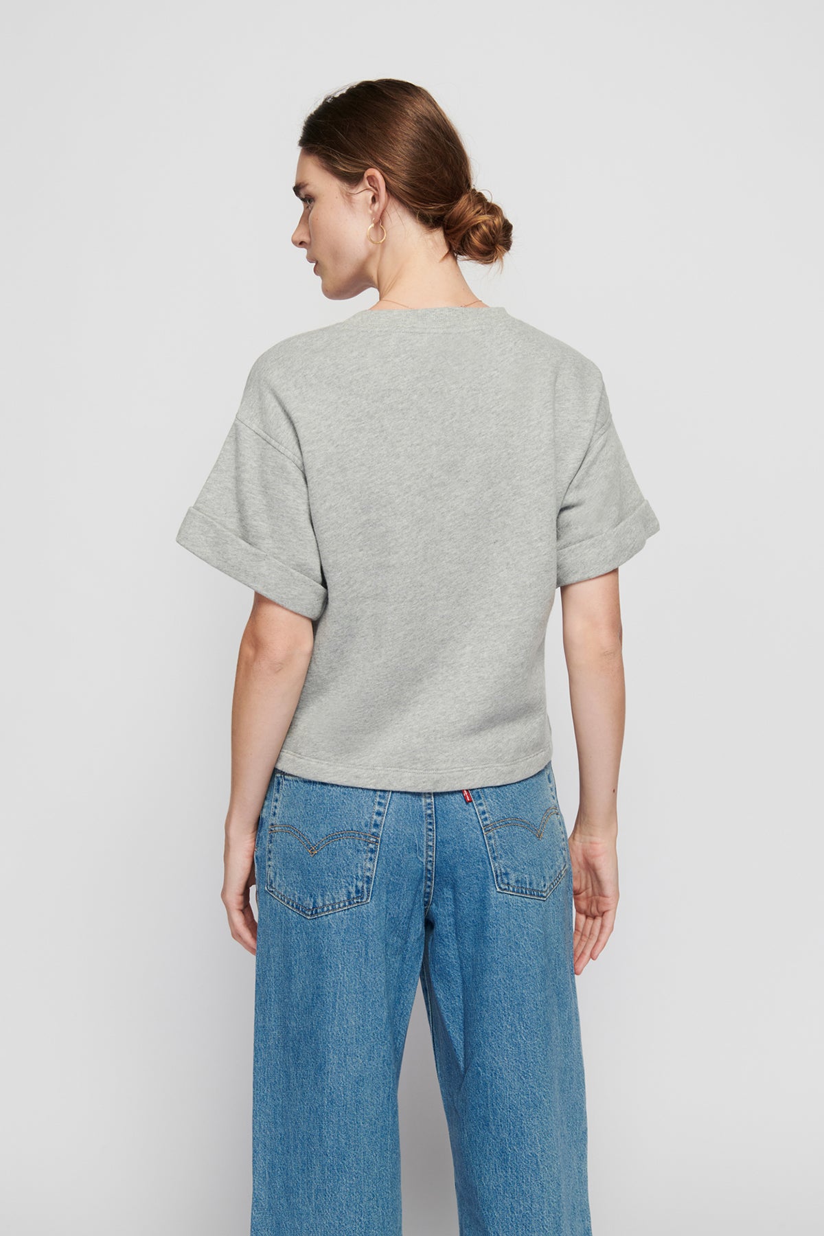 Person wearing a gray sweater and blue jeans on a plain background