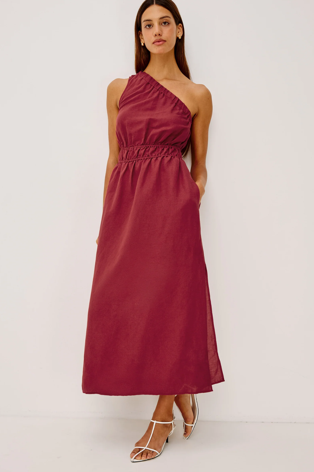 Woman wearing a burgundy one-shoulder dress on a white background