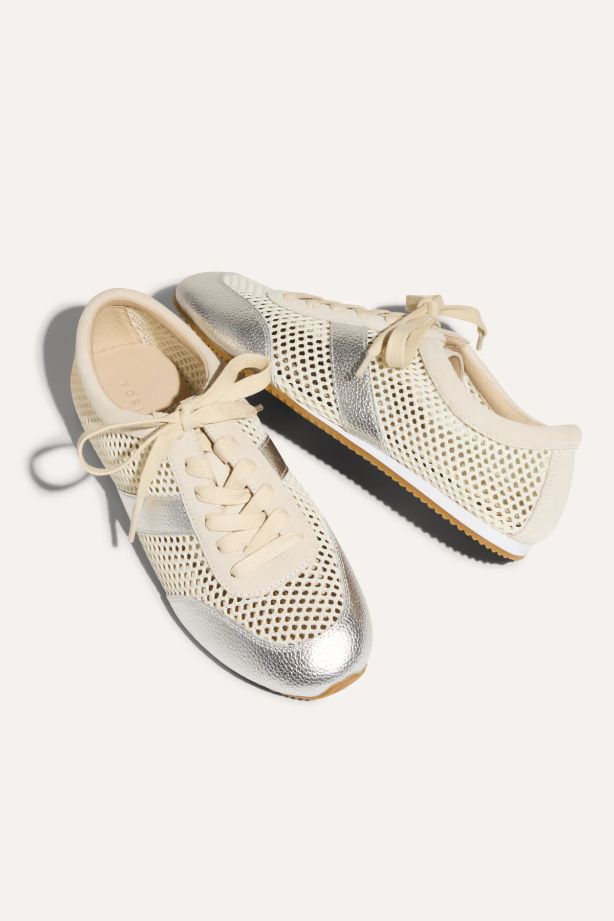 Pair of silver and cream sneakers on a white background