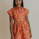 Woman wearing a colorful dress with a pattern on a plain background
