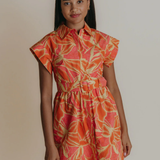 Woman wearing a colorful dress with a pattern on a plain background