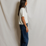 Woman wearing a white t-shirt and blue jeans standing against a plain white background