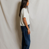Woman wearing a white t-shirt and blue jeans standing against a plain white background
