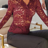 Woman wearing a red lace top sitting on a chair indoors.