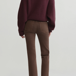 A model shown from the back wearing a dark burgundy knit sweater and brown ankle-length pants, paired with dark brown pointed-toe flats, against a light gray studio background.