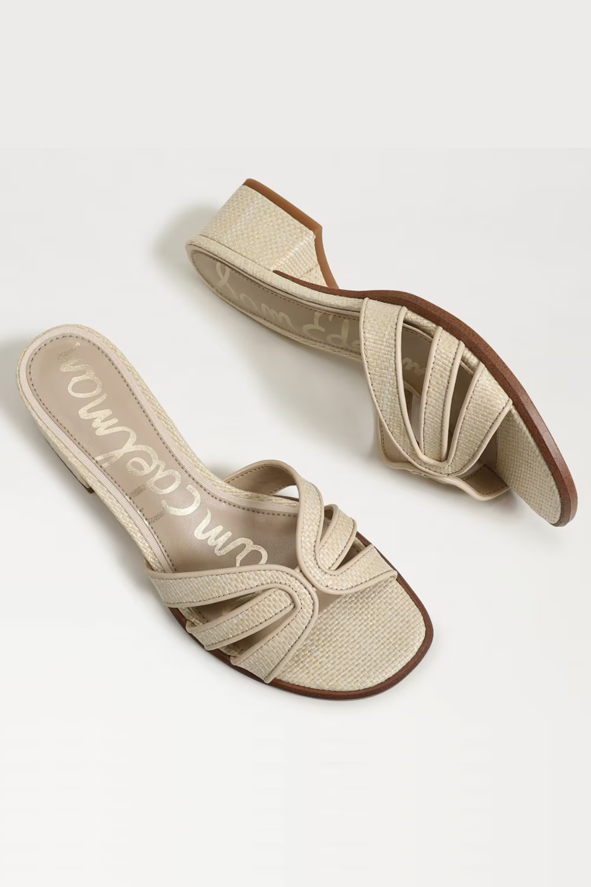 Pair of beige sandals with brown soles on a white background