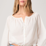 Woman wearing a white blouse and blue jeans against a plain background