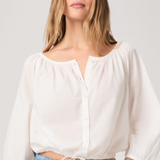 Woman wearing a white blouse and blue jeans against a plain background