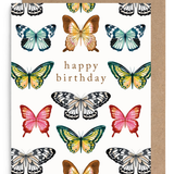 A square birthday card with a white background printed with multiple colorful butterfly illustrations and the words 'happy birthday' in the center, shown with a brown kraft envelope behind it on a white background.