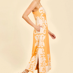 side view of woman inn orange embroidered midi dress 