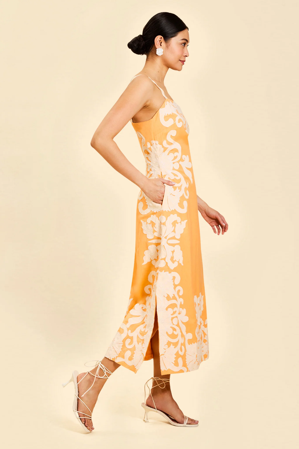 side view of woman inn orange embroidered midi dress 