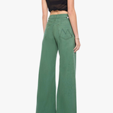 A woman shown from the back wearing green wide-leg pants, a black sleeveless crop top, and metallic high heels against a plain light gray studio background.