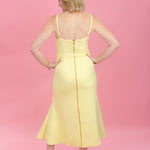 Woman wearing a yellow dress against a pink background