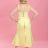 Woman wearing a yellow dress against a pink background