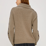 Woman wearing a beige sweater with black accents on a white background