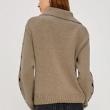 Woman wearing a beige sweater with black accents on a white background