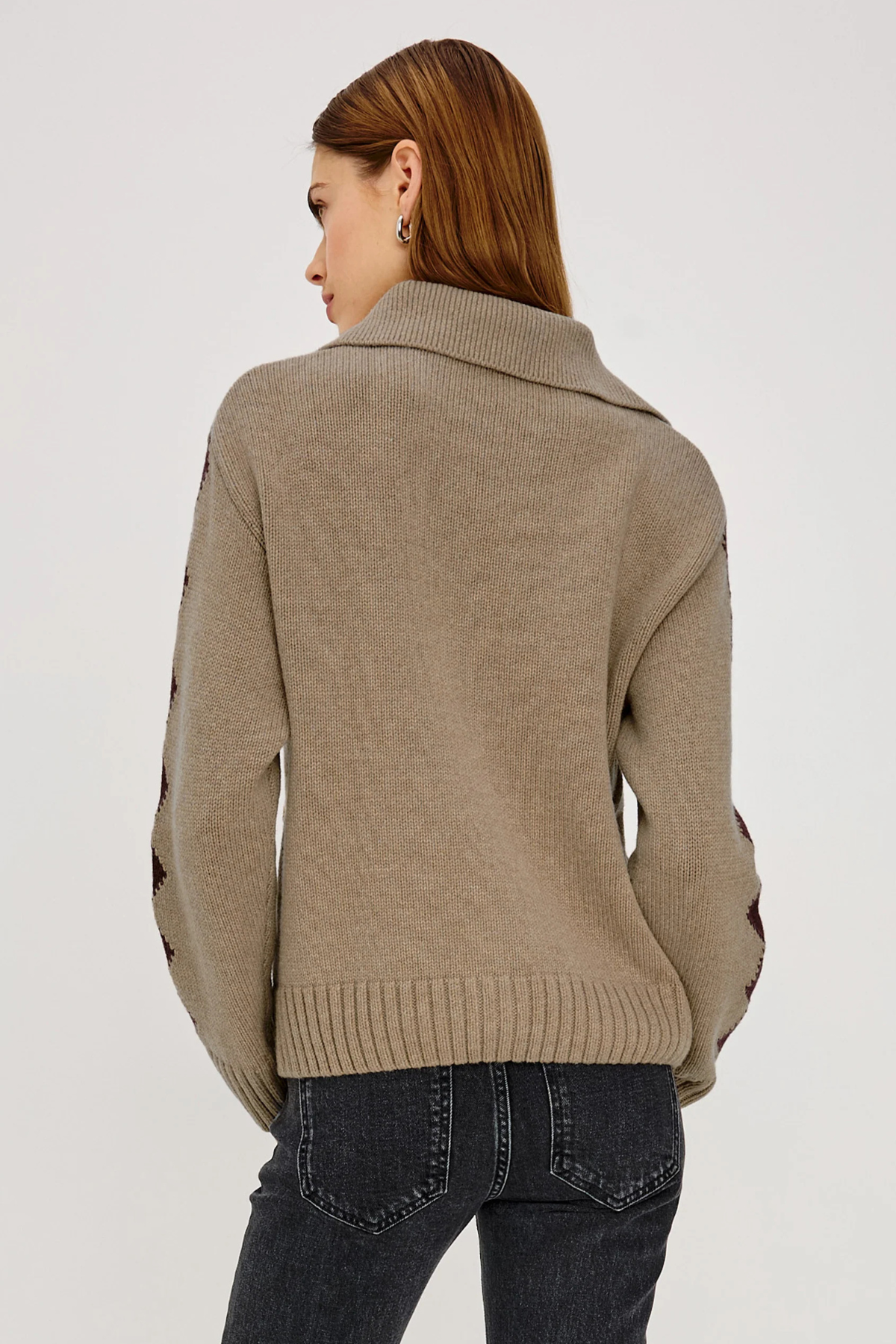 Woman wearing a beige sweater with black accents on a white background