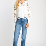 Woman wearing a white lace blouse and blue jeans on a white background