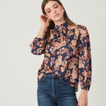 Woman wearing a floral blouse and blue jeans on a light gray background