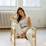 woman in char in striped tank and white denim 