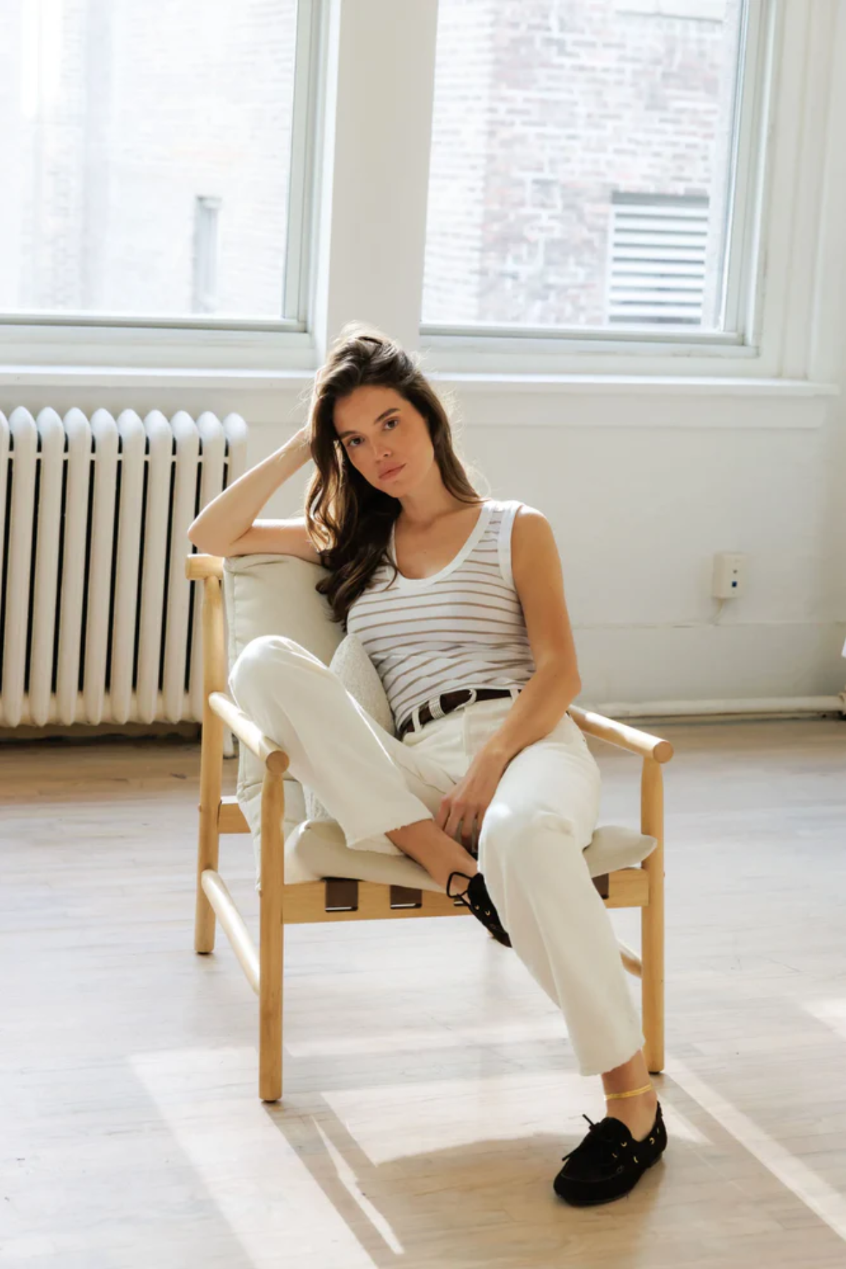 woman in char in striped tank and white denim 