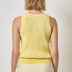 Woman wearing a yellow sleeveless top and striped skirt on a plain background