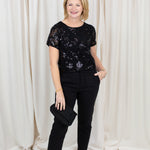 Woman wearing black chino trousers with a front hem split, styled with heels.