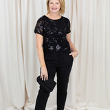 Woman wearing black chino trousers with a front hem split, styled with heels.