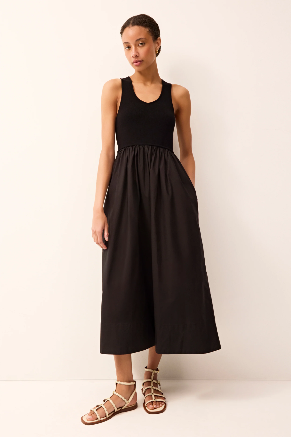 Woman wearing a black sleeveless dress against a white background