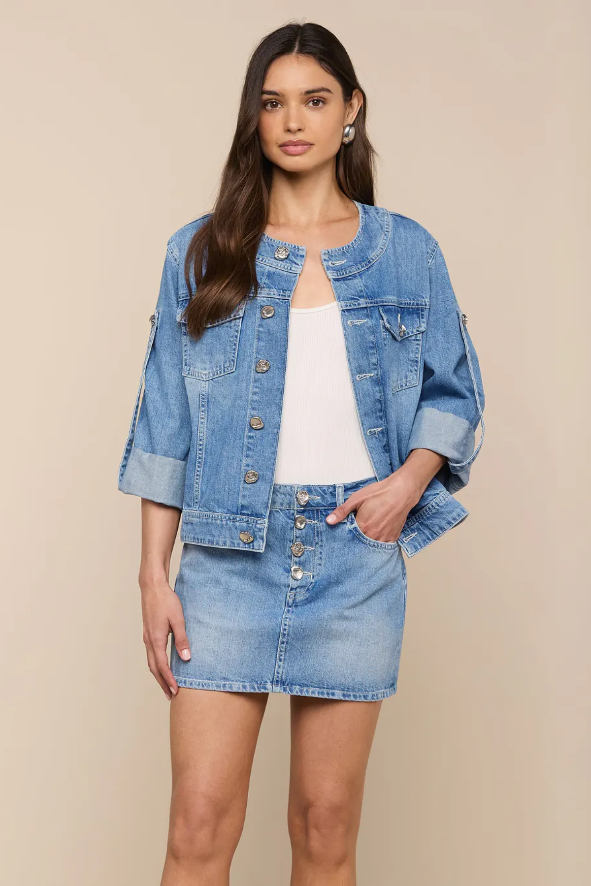 Woman wearing a denim jacket and skirt on a beige background