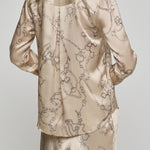 Beige satin pajama set with intricate patterns on a plain background