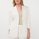 Woman wearing a white blazer and shorts set on a plain background