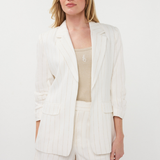 Woman wearing a white blazer and shorts set on a plain background