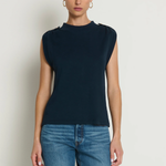 Woman wearing a navy sleeveless top and blue jeans against a white background