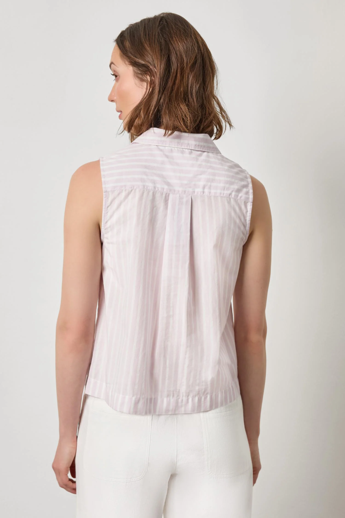 Woman wearing a sleeveless striped shirt against a plain background