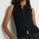 Woman wearing a black sleeveless button-up top against a white background