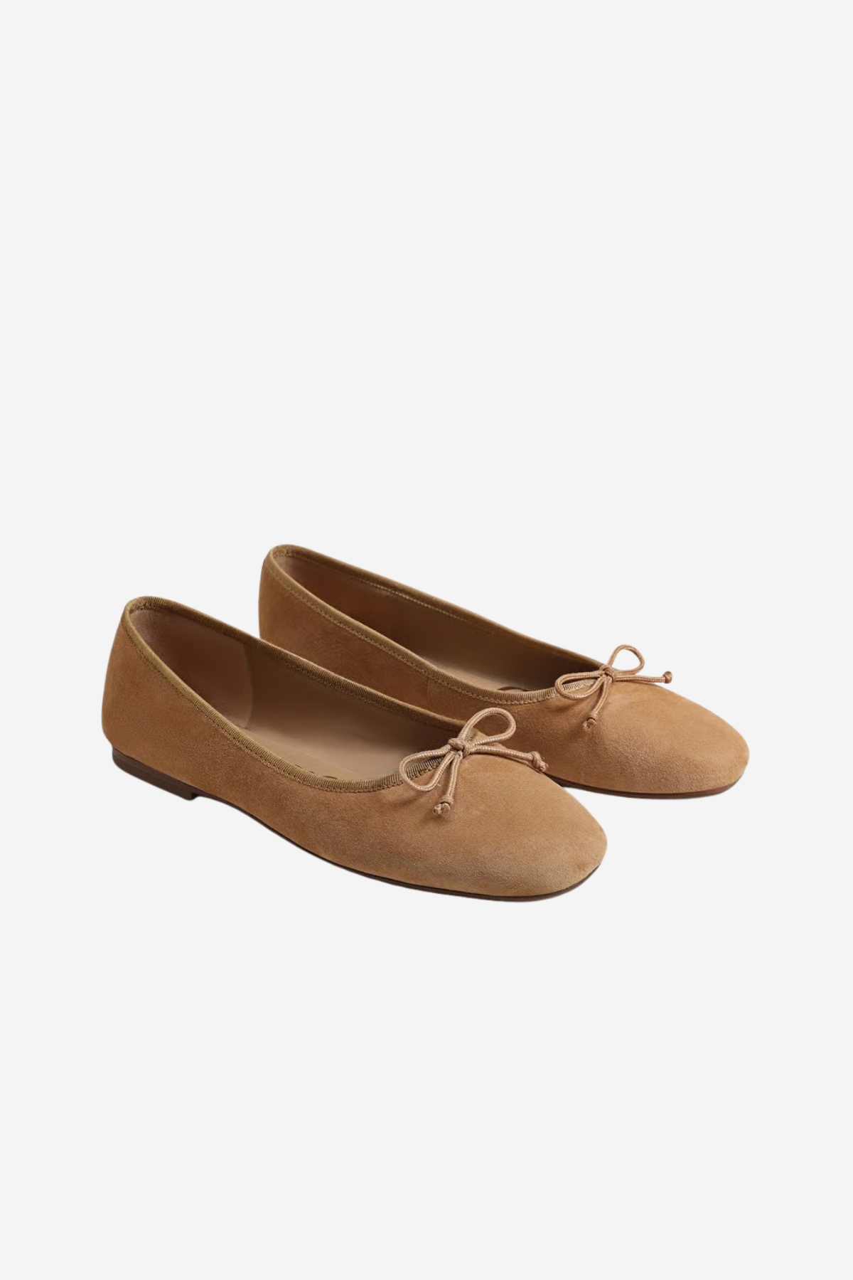 A pair of tan suede ballet flats with small bow details on the toes, shown against a plain light gray background.