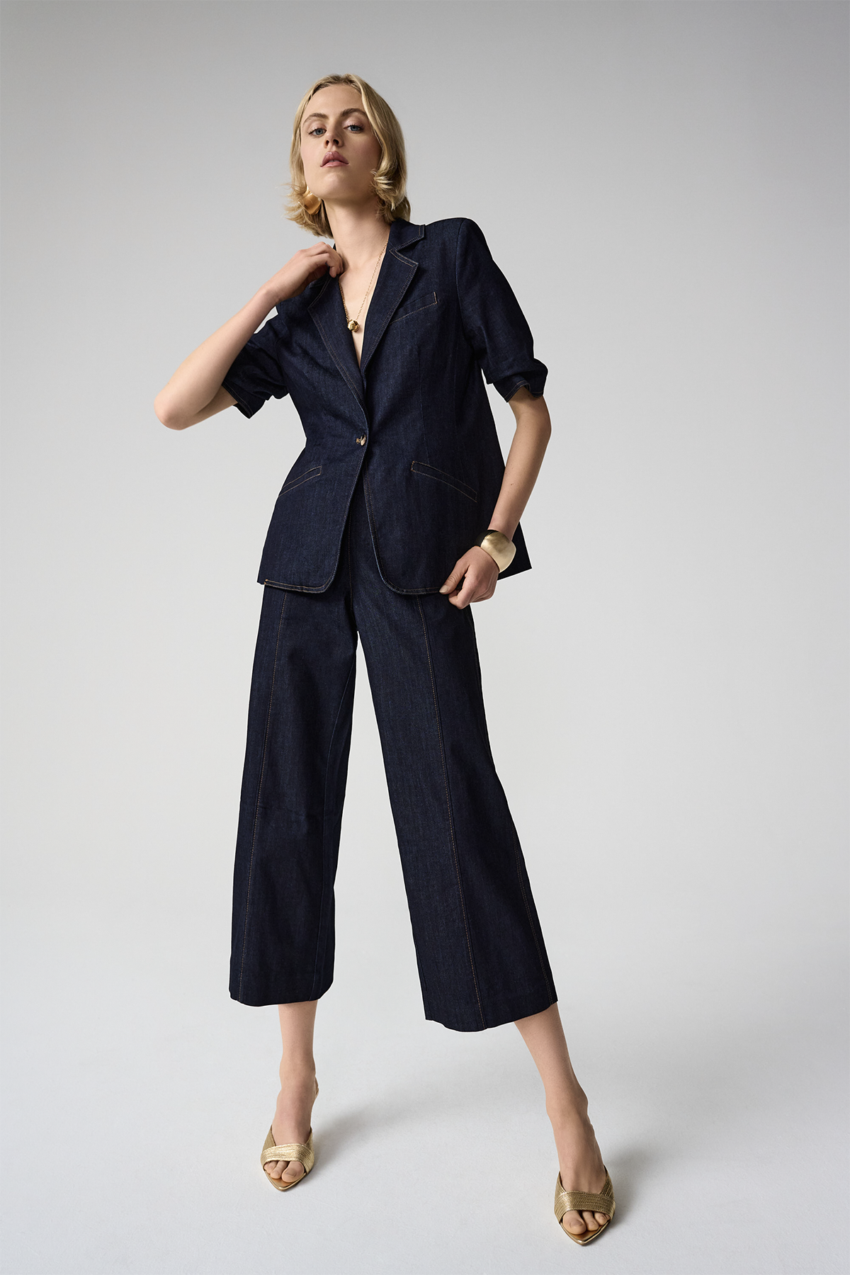 Woman wearing a navy blue suit with wide-leg pants on a light gray background