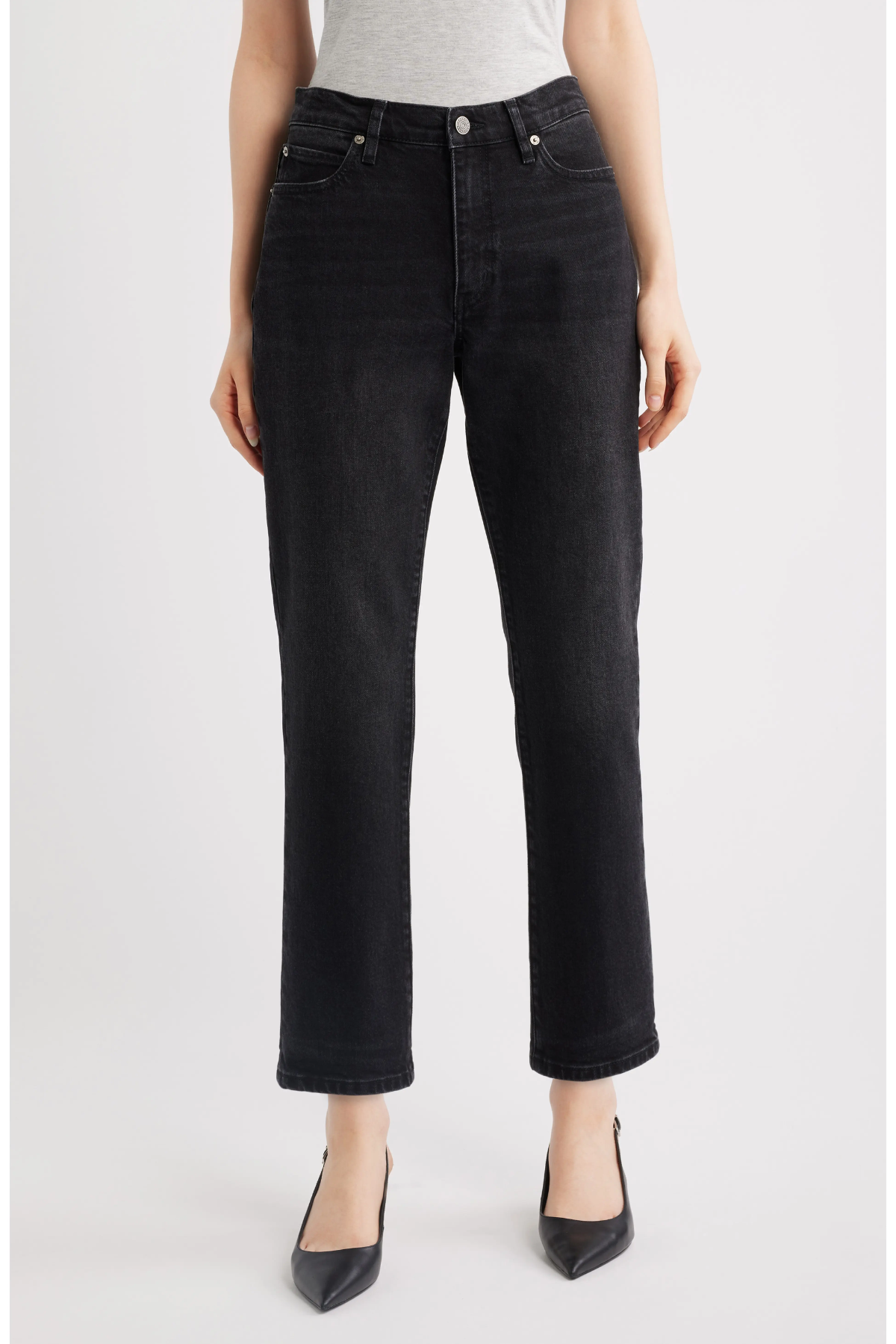 A model wearing black cropped straight-leg jeans with a gray top and black pointed-toe heels, shown from the waist down against a light gray studio background.